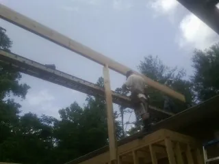 Carpenter setting a ridge beam over a new addition frame — Ice Dam Removal by Roofing Brothers in Millerton