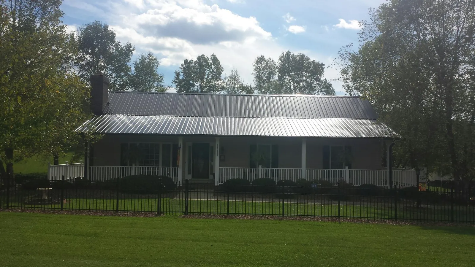 Gray metal roof on a brick ranch with a full width front porch — Gutter Guard Installation work by our crew in Millerton