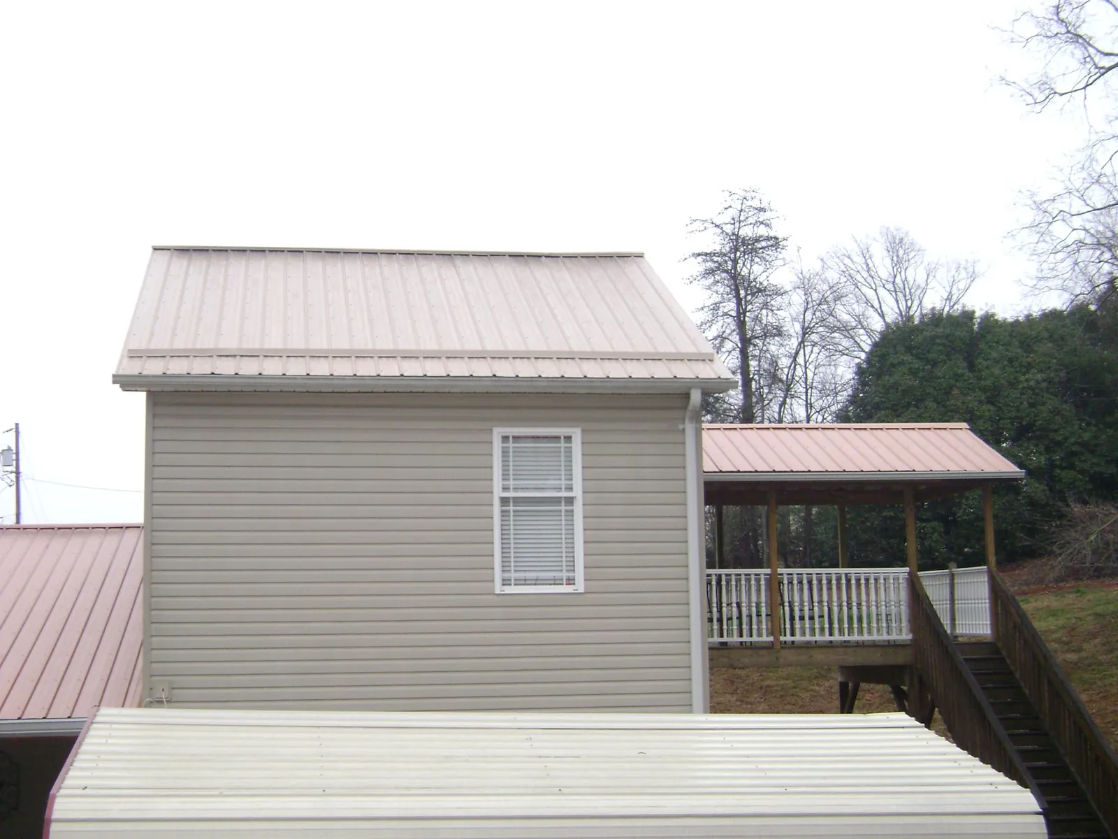 Tan metal roofs on a two story addition and attached porch, from a Roof Replacement job in Millerton